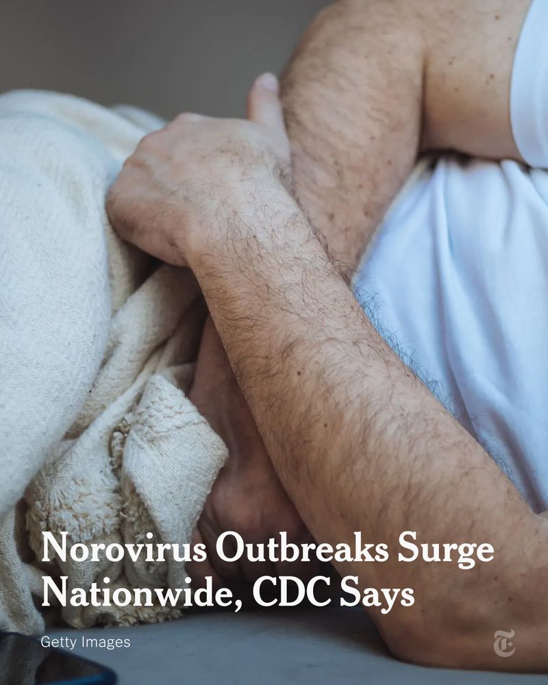 A man in a white T-shirt is pictured clutching his stomach while lying in bed. Headline reads: "Norovirus Outbreaks Surge Nationwide, CDC Says." Photo credit: Getty Images. 