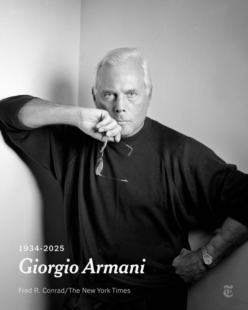 Giorgio Armani posing in a black sweater while holding a pair of glasses. Text says his name and 