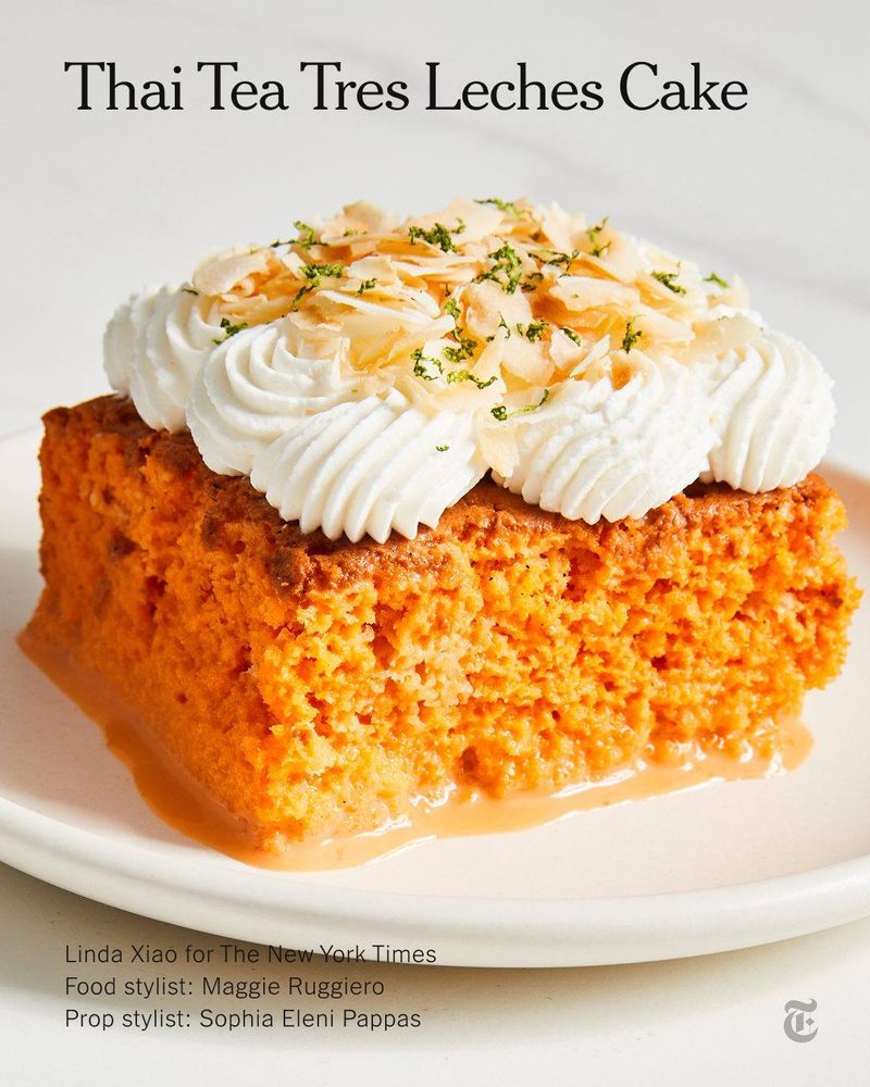 A vibrant orange slice of Thai Tea Tres Leches Cake topped with whipped cream and sliced almonds.