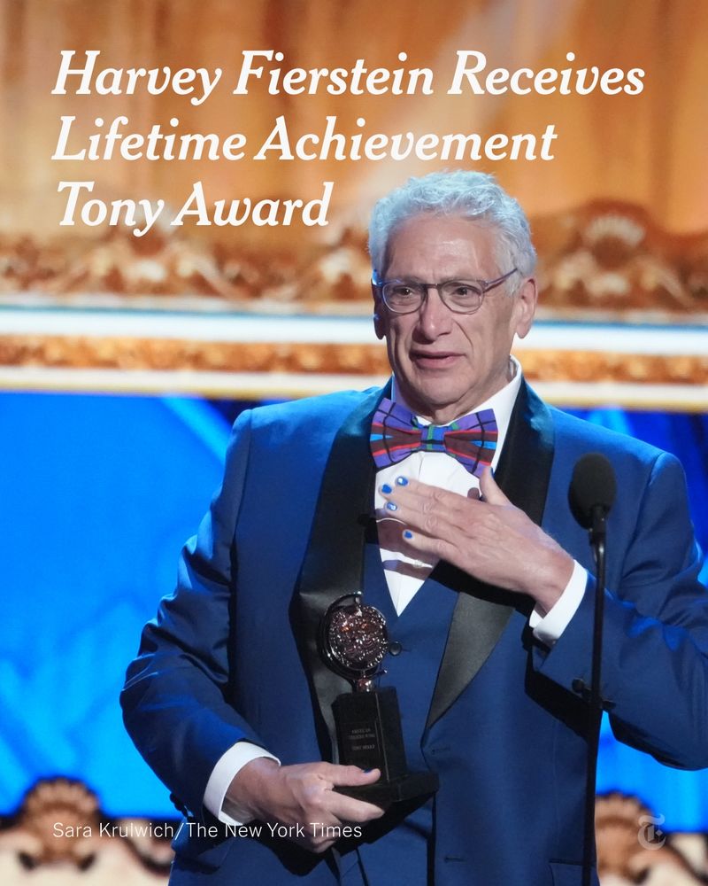 The actor Harvey Fierstein, with short gray hair and wearing a blue suit and a colorful bow tie, holds a Tony Award, touching his hand to his chest. Photo by Sara Krulwich/The New York Times