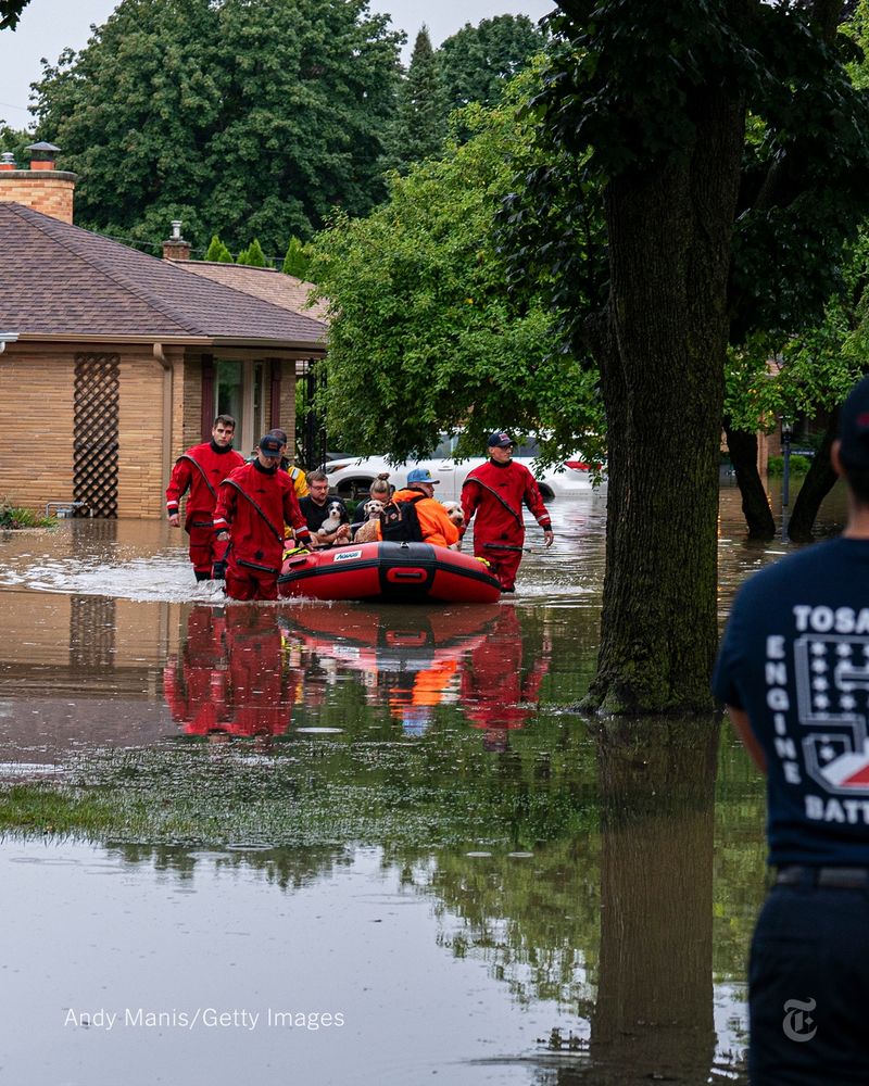 Rescuers in red suits helping residents in an inflatable raft who were stranded by flooding in Wisconsin on Sunday.  Photo by Andy Manis/Getty Images