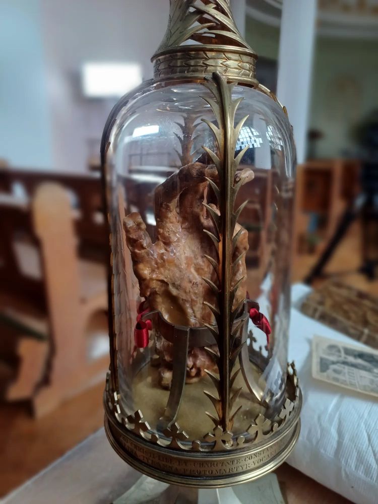 a shrivelled mummified hand in a case made of brass and glass 