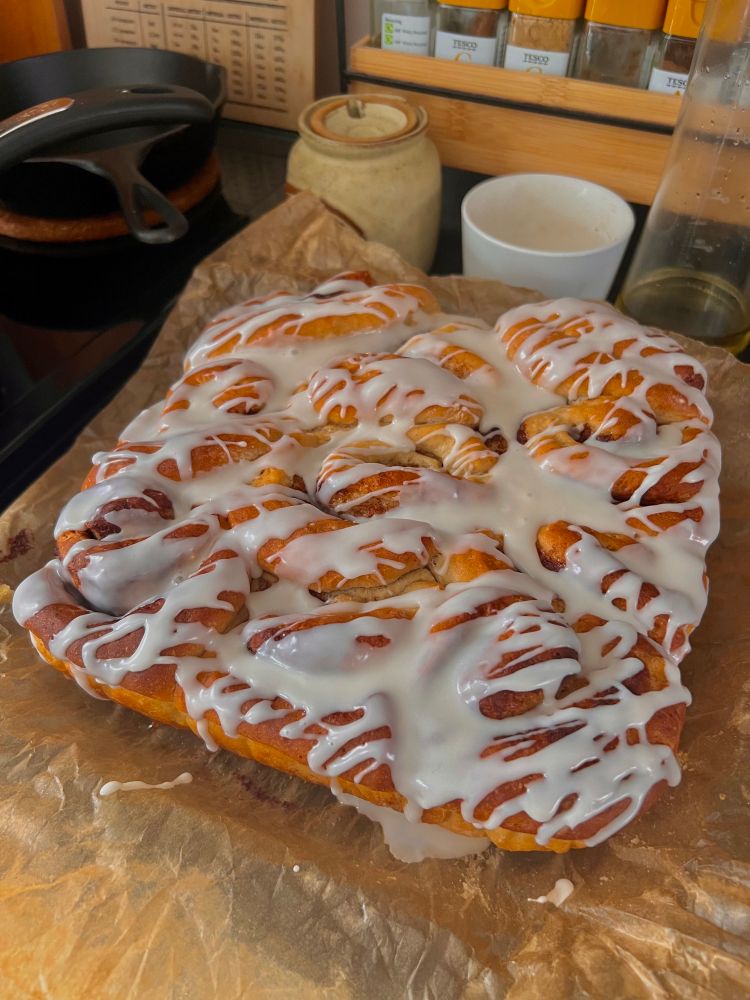 cinnamon rolls on parchment paper with maybe a little too much frosting on them 