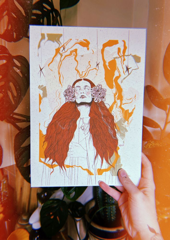 anni’s hand holding a drawing of florence welch of florence and the machine with a marbled yellow and green background there are plants in the background