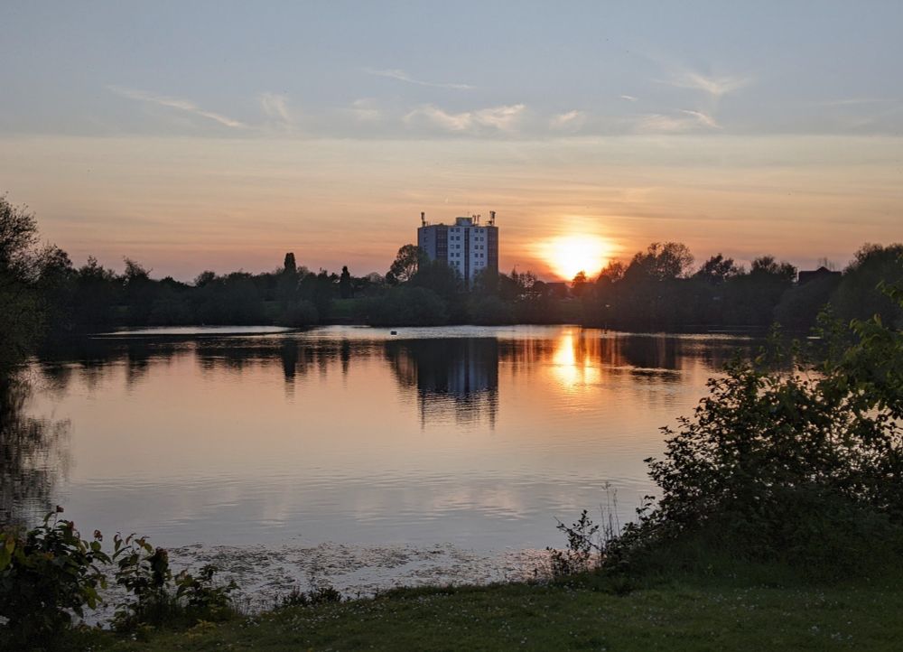 Scene of lake in an urban context with sunset behind