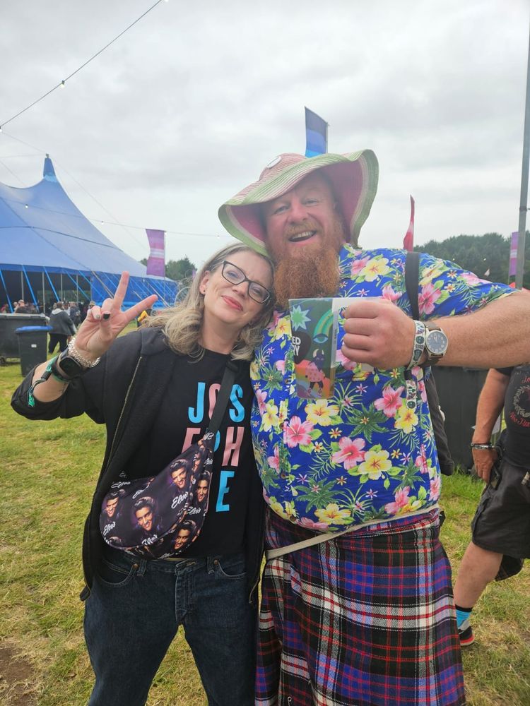 Liz, a woman in specs and prodigious musician is hugged by Doc, a clod-hopper of a bloke with a big ginger beard and questionable musicianship. They are both at Bearded Theory festival where Liz has just played on the main stage with Terrorvision.