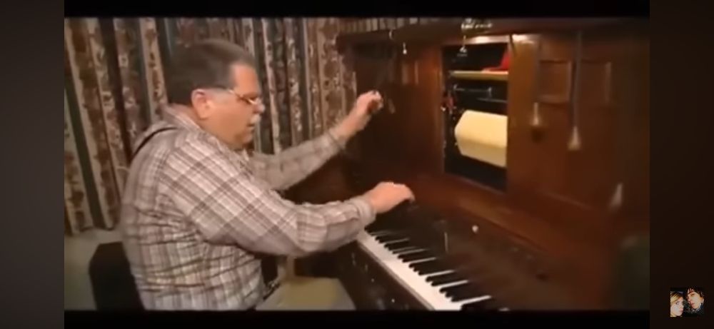 an older gentleman playing an instrument called a photoplayer, which was used for scoring silent films, often as live performance. it sounds like those old vaudeville comedy songs, with all the whistles and cowbells and crashing cymbals and shit