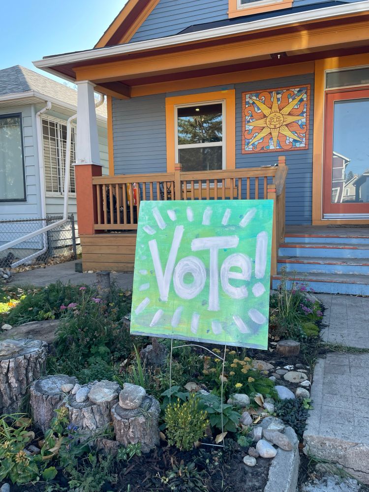 A hand-painted lawn sign that says, "vote!"
