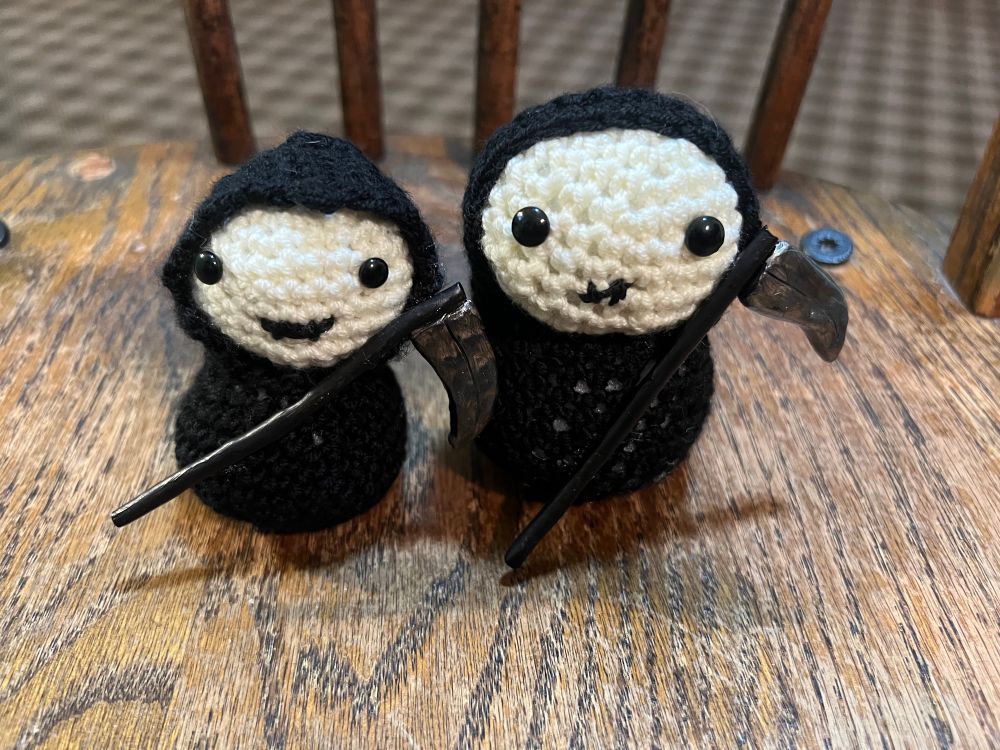 Two crocheted black and white grim reapers with scythes.  