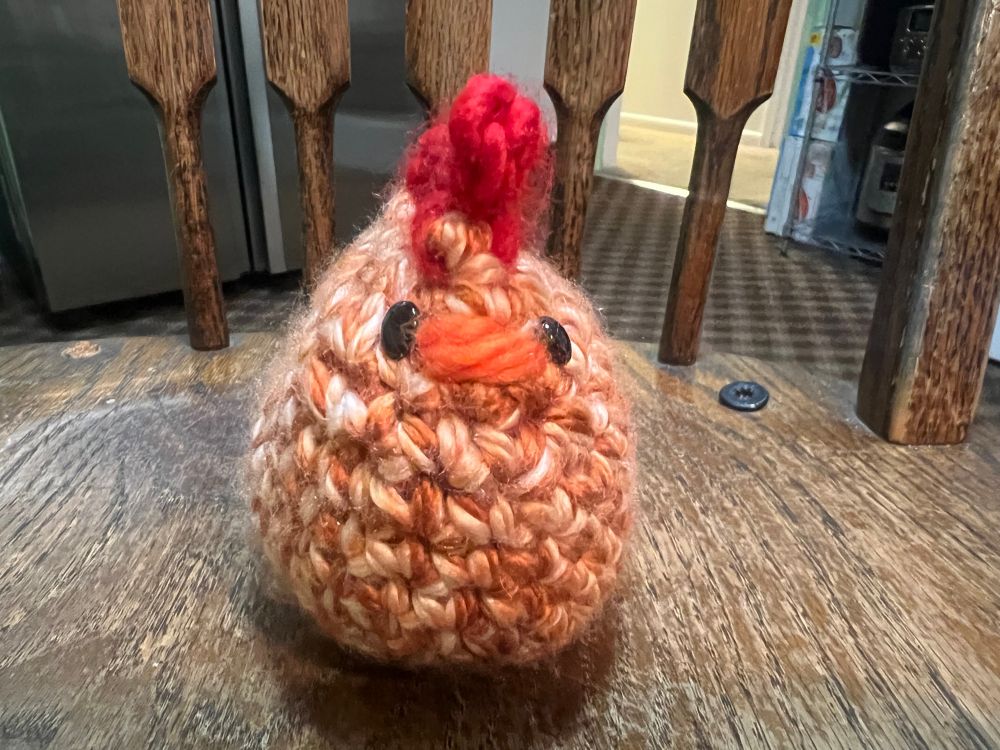 Orange and white stuffed crochet chicken from front.