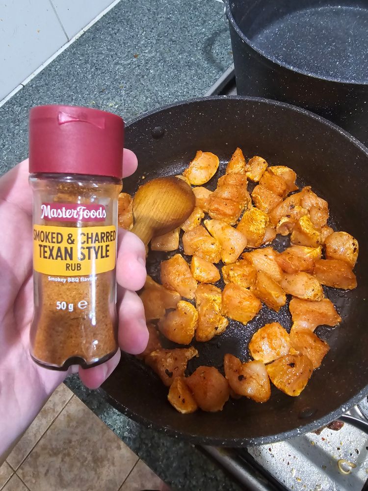 Uncooked chicken in a pan with a masterfoods brand smoked and charred Texan style rub seasoning in the foreground