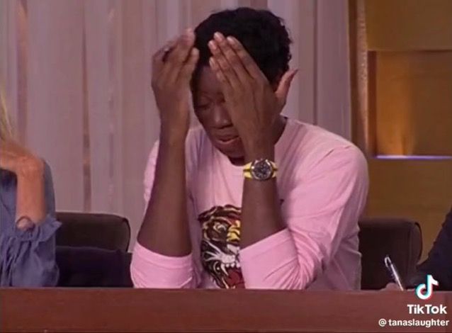 picture of miss j. alexander with her hands almost on her forehead, looking stressed while maintaining beauty. she’s wearing a pink graphic, long sleeve tshirt with a growling tiger on it