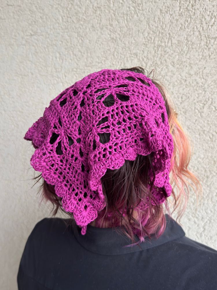 Girl wearing a magenta crocheted butterfly bandana facing away from the camera at an angle