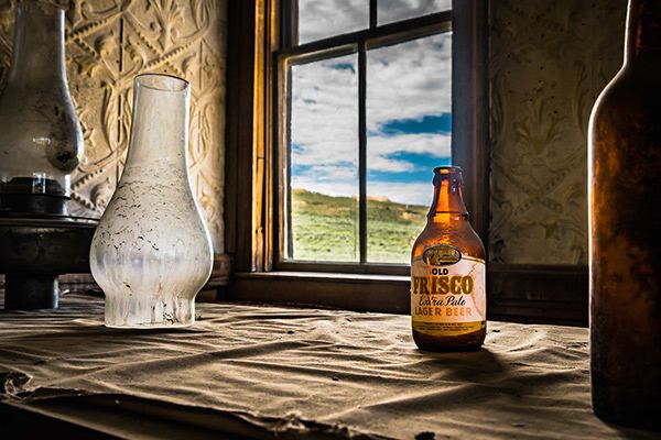 An empty bottle of beer left on a bar in a ghost town.