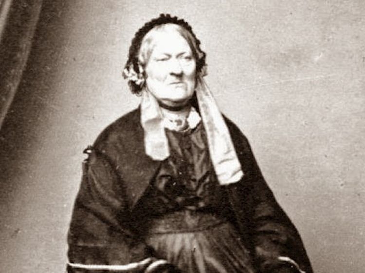 Photo of Lily Maxwell. She is an older white woman in Victorian widow's weeds (lots of black silk and lace).
