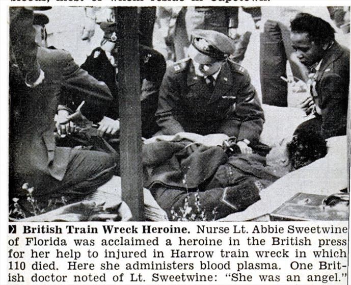 Abbie Sweetwine, a black woman in USAF uniform, holding a plasma bag as white male military doctors treats a patient lying on the platform. Text reads British Train Wreck Heroine. Nurse Lt Abbie Sweetwine of Florida was acclaimed a heroine in the British press for her help to injured in Harrow train wreck in which 110 died. Here she administers blood plasma. One British doctor noted of Lt Sweetwine: "she was an angel."