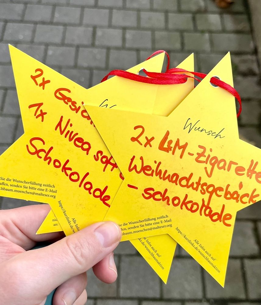 Drei gelbe Papiersterne mit drauf geschriebenen Wünschen für Weihnachten 