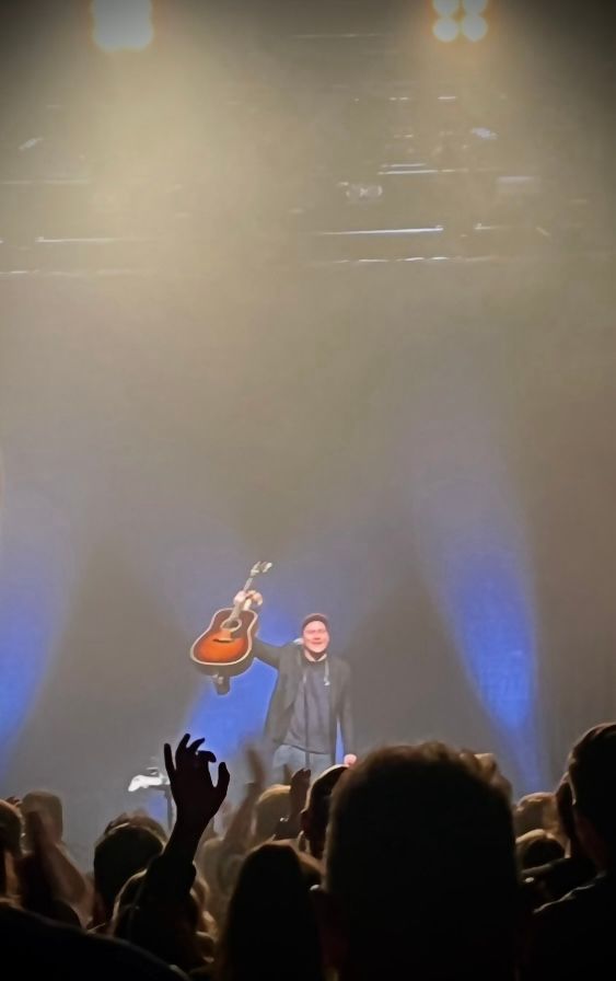 Der Sänger Thees Uhlmann hält zum Applaus seine braune Gitarre in die Luft