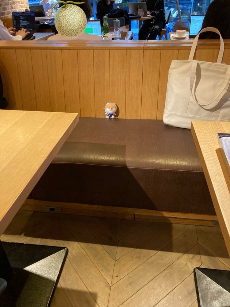 FREEMAN CAFE の店内。茶色ベンチにトートバックとポリまるキーチェーンが置かれている。