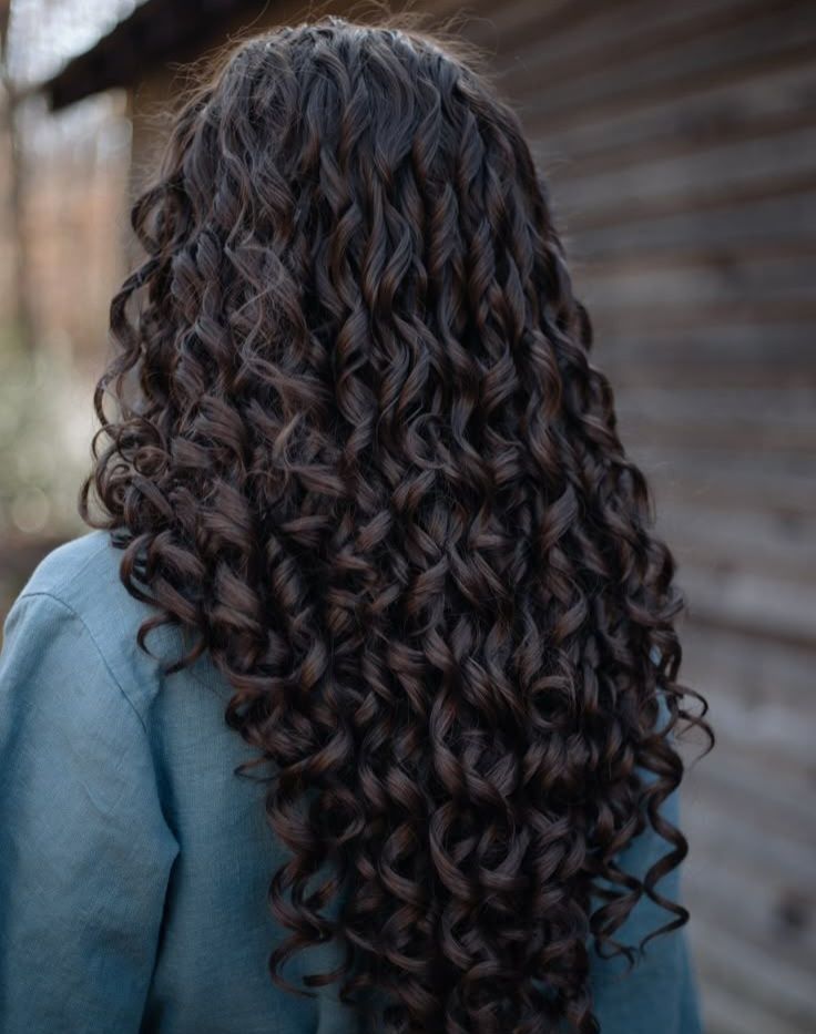 A person from the back wearing blue. Their hair is dark and curly. 