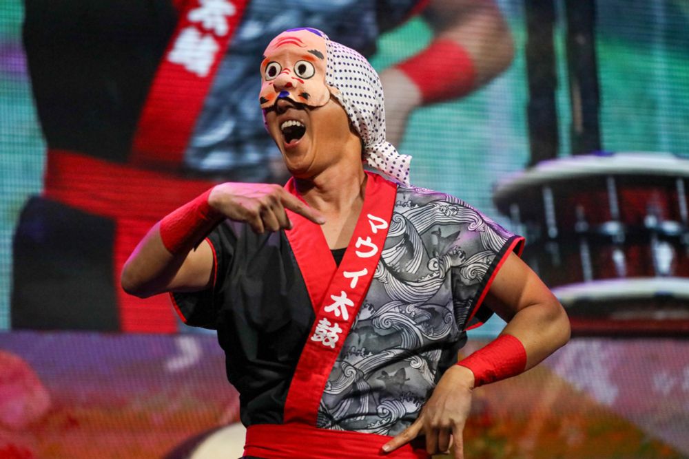 taiko drummer with mask gesticulates 
