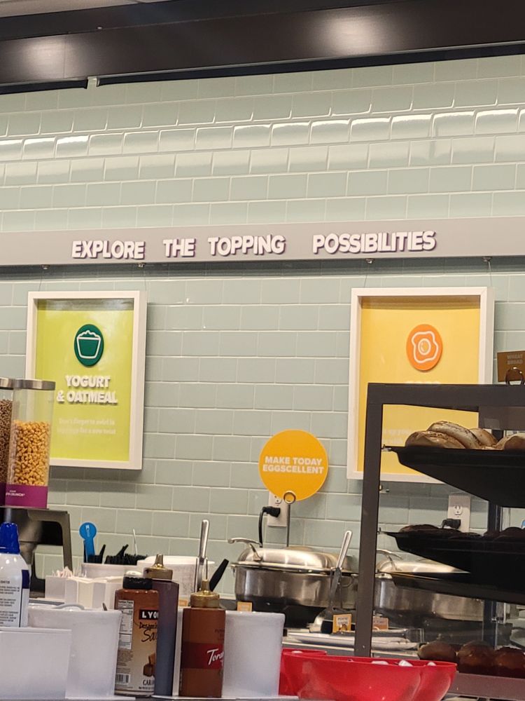 A sign at a breakfast bar that reads: "EXPLORE THE TOPPING POSSIBILITIES."