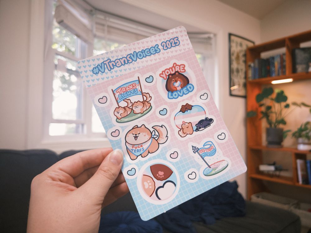 A hand holding up SmilkyShake’s #VTransVoices 2025 sticker sheet!