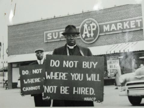 Black Man holding sign saying “Do not buy where you won’t be hired”. This is civil rights era photo.