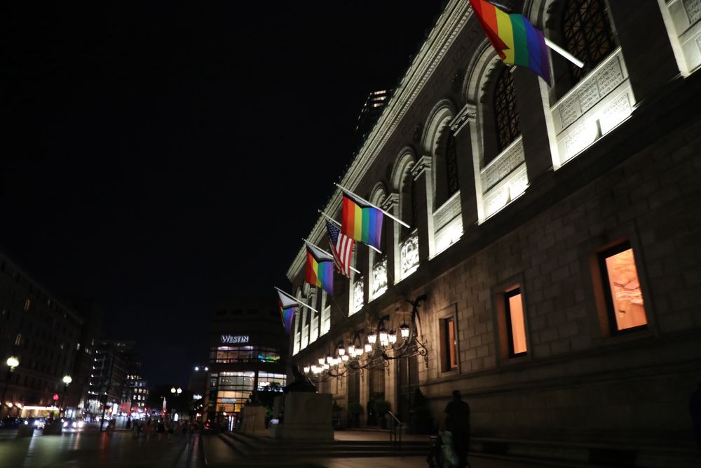 Pride flags along the colonnade windows of a building in downtown Boston