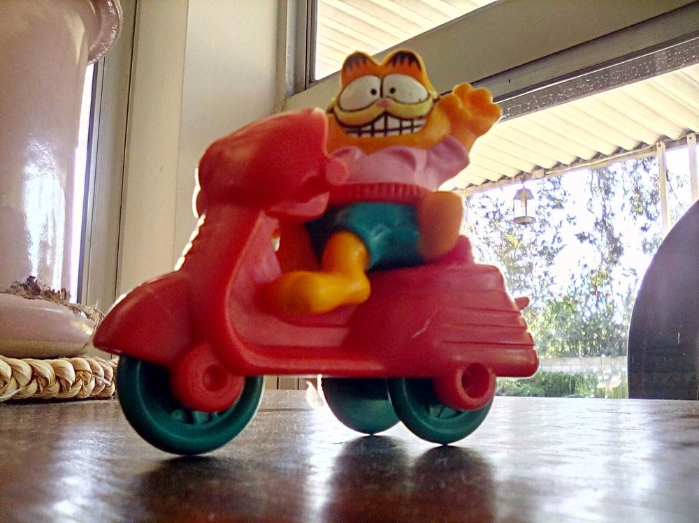 Grinning Garfield figurine atop a red scooter with blue wheels. McDonald's toy I believe.