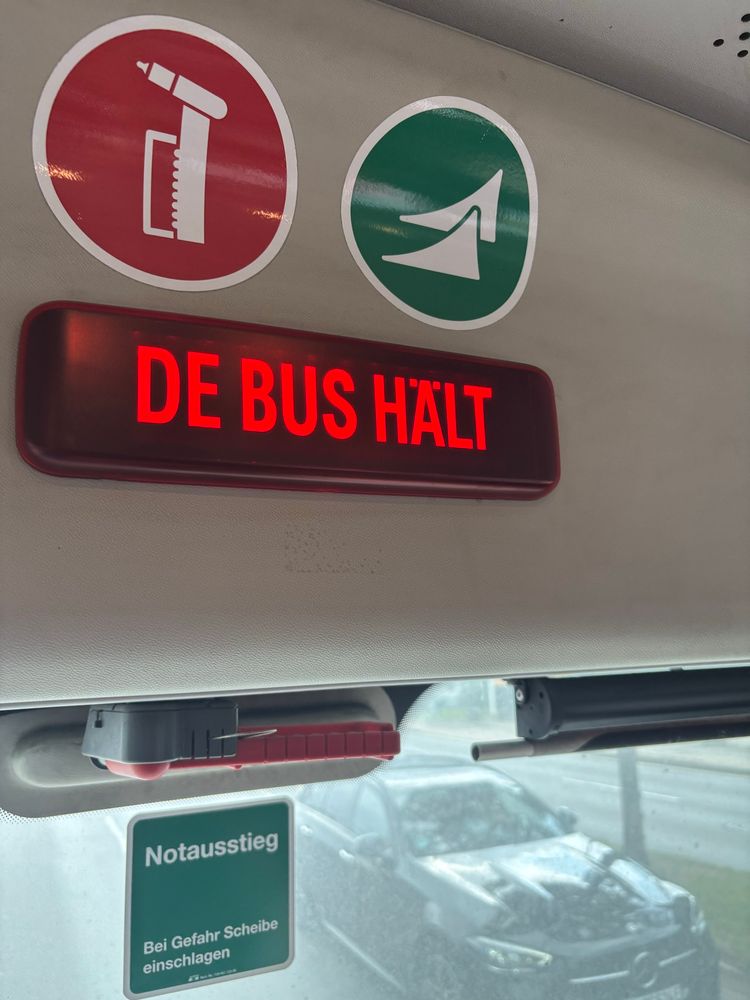 Tussen Mönchengladbach en Venlo rijden geen treinen. De dienstregeling wordt gehandhaafd door een bus. De bus codeswitcht: een monitor waarop staat „de bus hält“.