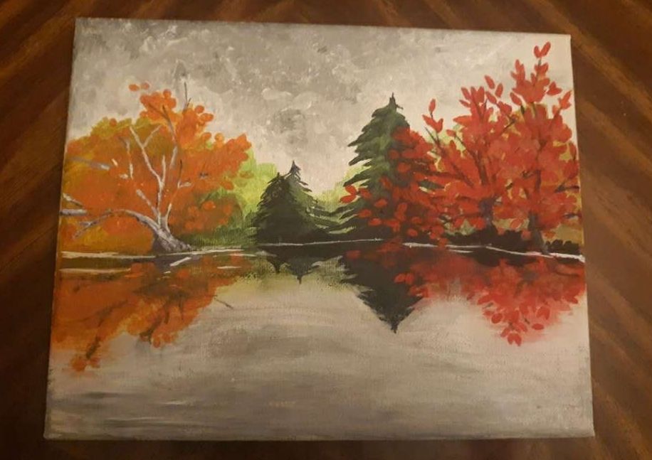 a painting of an autumn scene by a lake, the sky is gray and cloudy, dark enough that it might rain
The vibrant reds, golds, and dark greens reflect in the water