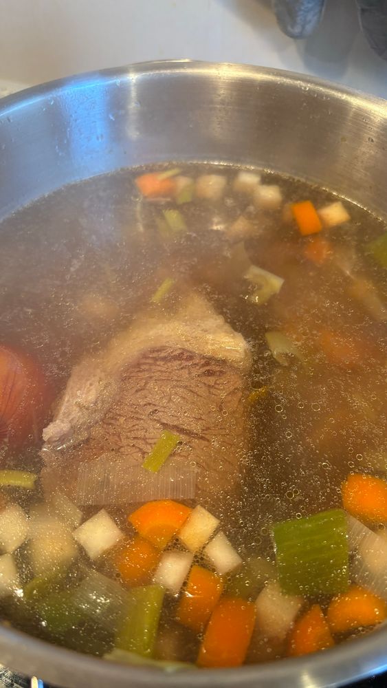 Ein Foto einer klaren Brühe in einem Topf mit Tafelspitz, Karotten, Lauch und Sellerie