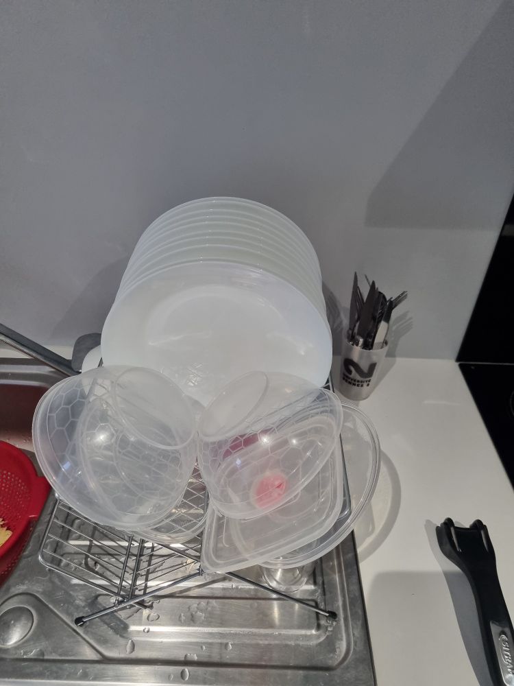 Photo d'un évier remplis de vaisselle 
12 assiettes sont en train de sécher et quelques tupperwares 