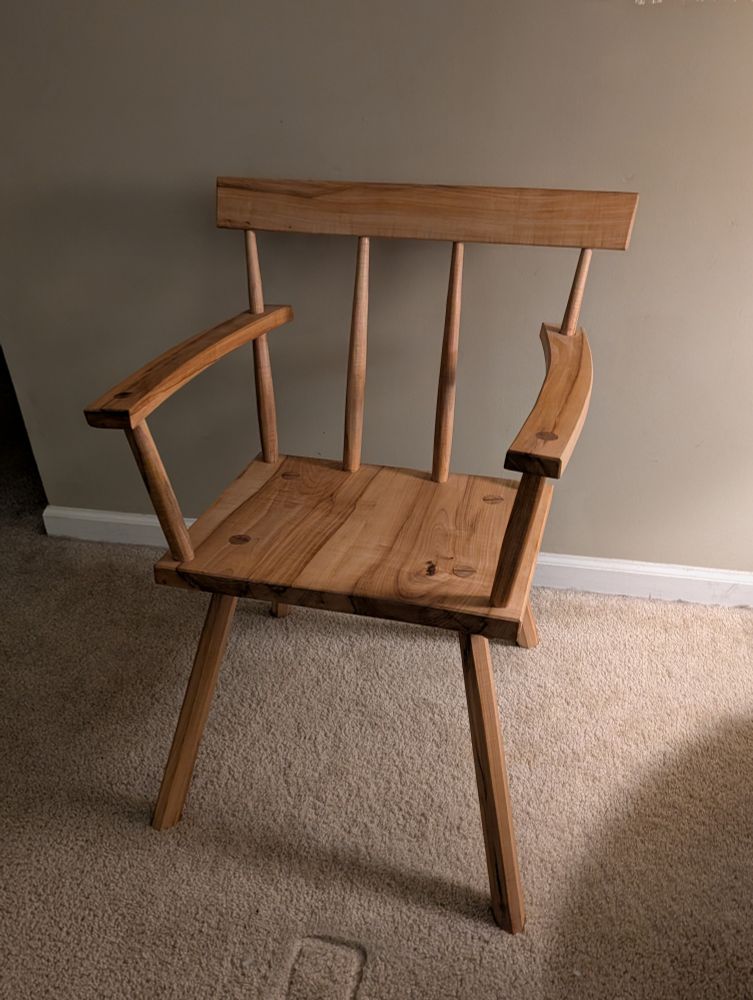 simple wooden chair with a flat seat. four back posts and two arms