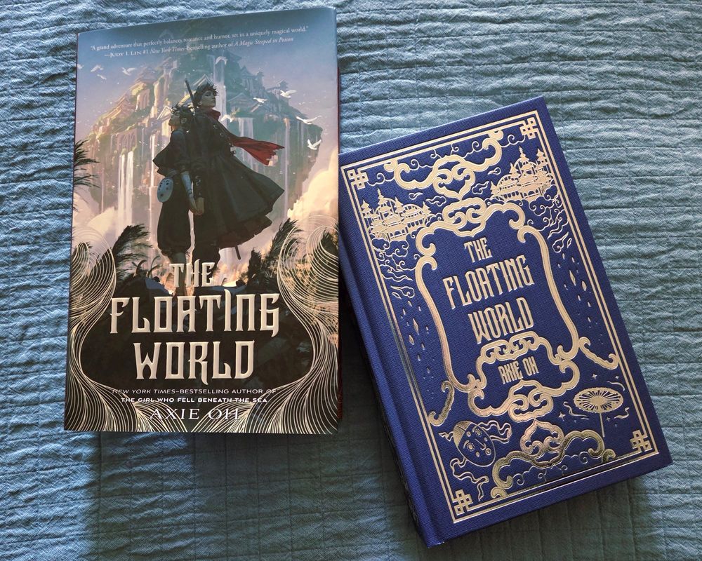A copy of The Floating World by Axie Oh sits on a blue quilt