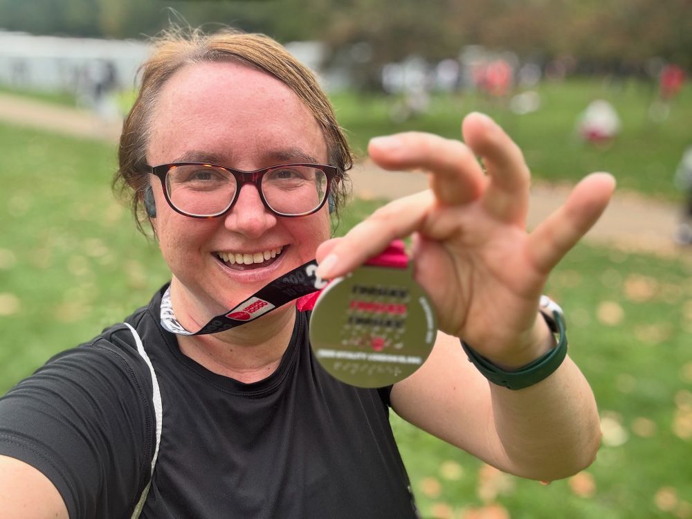 Me holding up a finisher’s medal to the camera whilst standing in the middle of a park.