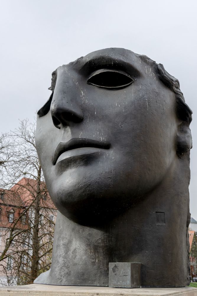 Die große Skulptur Centurione von Igor Mitoraj zeigt das Fragment eines jugendlichen Kopfes, dem große Teile fehlen, zum Beispiel das rechte Auge und der gesamte Hinterkopf. Die Bronzeplastik ist von dunkler Farbe und befindet sich in der Altstadt von Bamberg.