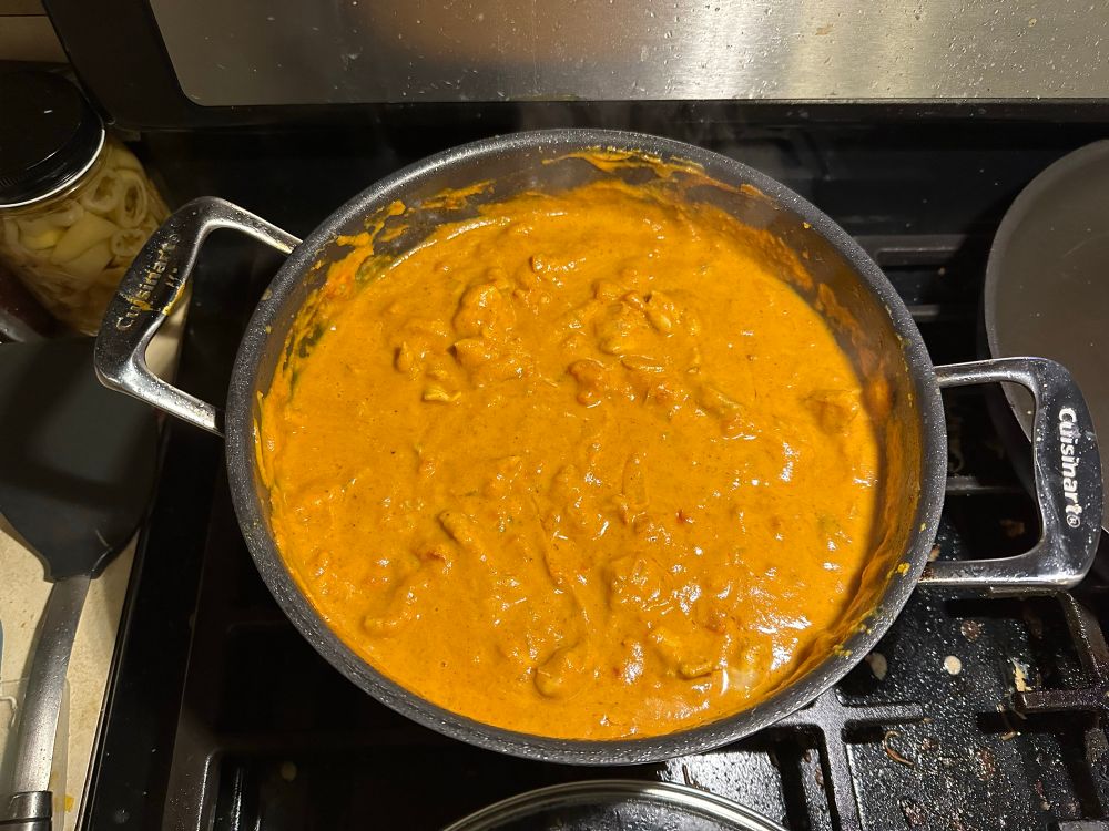A pot of pumpkin curry with chopped chicken thighs.