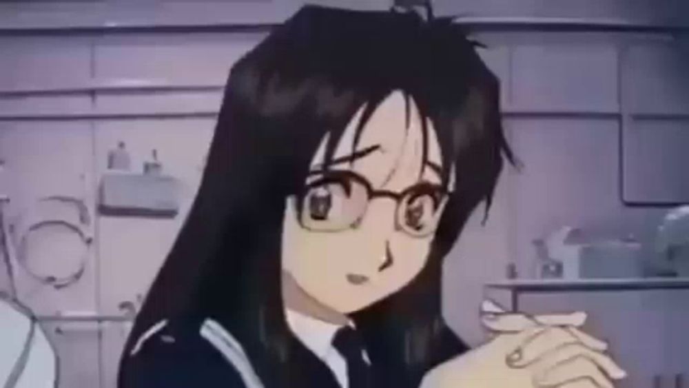 a girl with long black hair and glasses is sitting in a room .