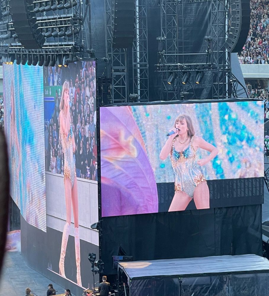 Taylor Swift at The Eras tour in Edinburgh night 1 wearing blue and gold lover bodysuit while singing on screen