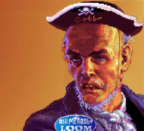 Un hombre calvo, con una barba rala que lleva un sombrerito de pirata que pone "Cobb" y una pegatina donde pone "Ask me about Loom"