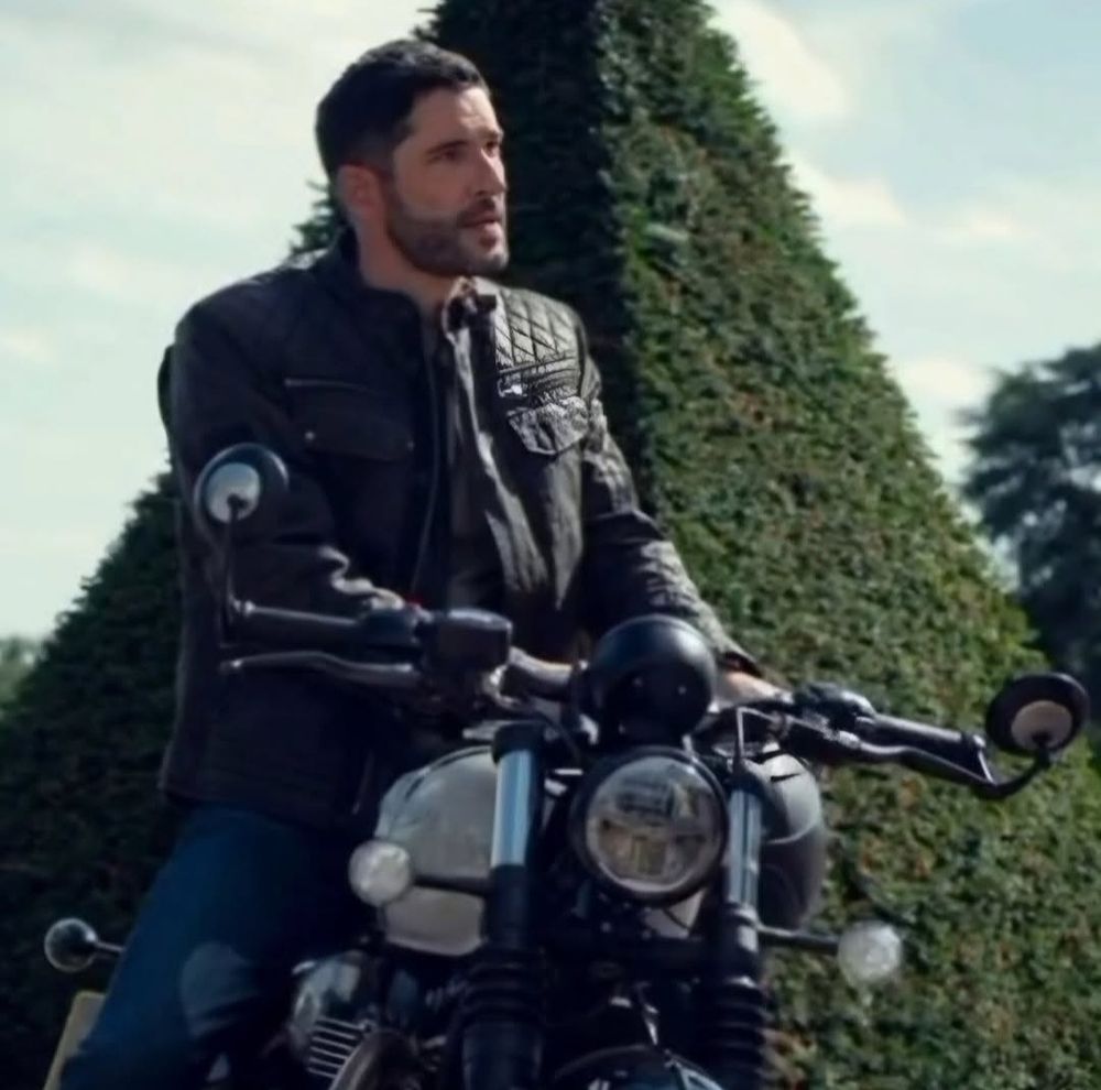 Tom Ellis in black leather jacket on a motorbike.