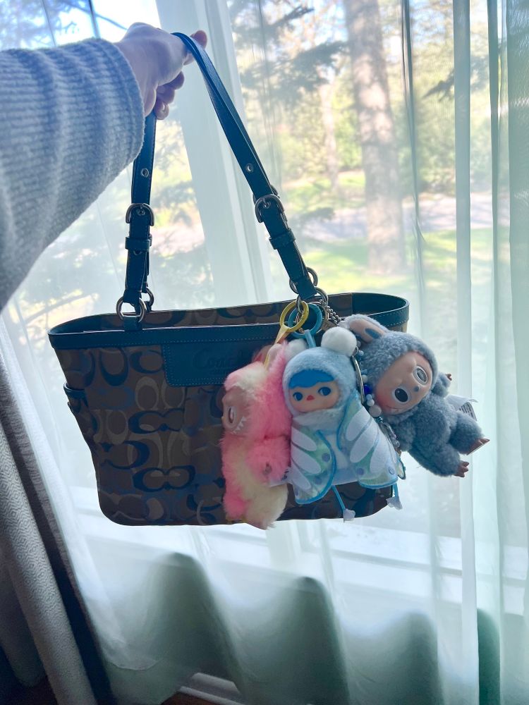A blue monogram Coach purse adorned with three soft elves. Loyalty, Butterfly Baby and Sea Salt Coconut.