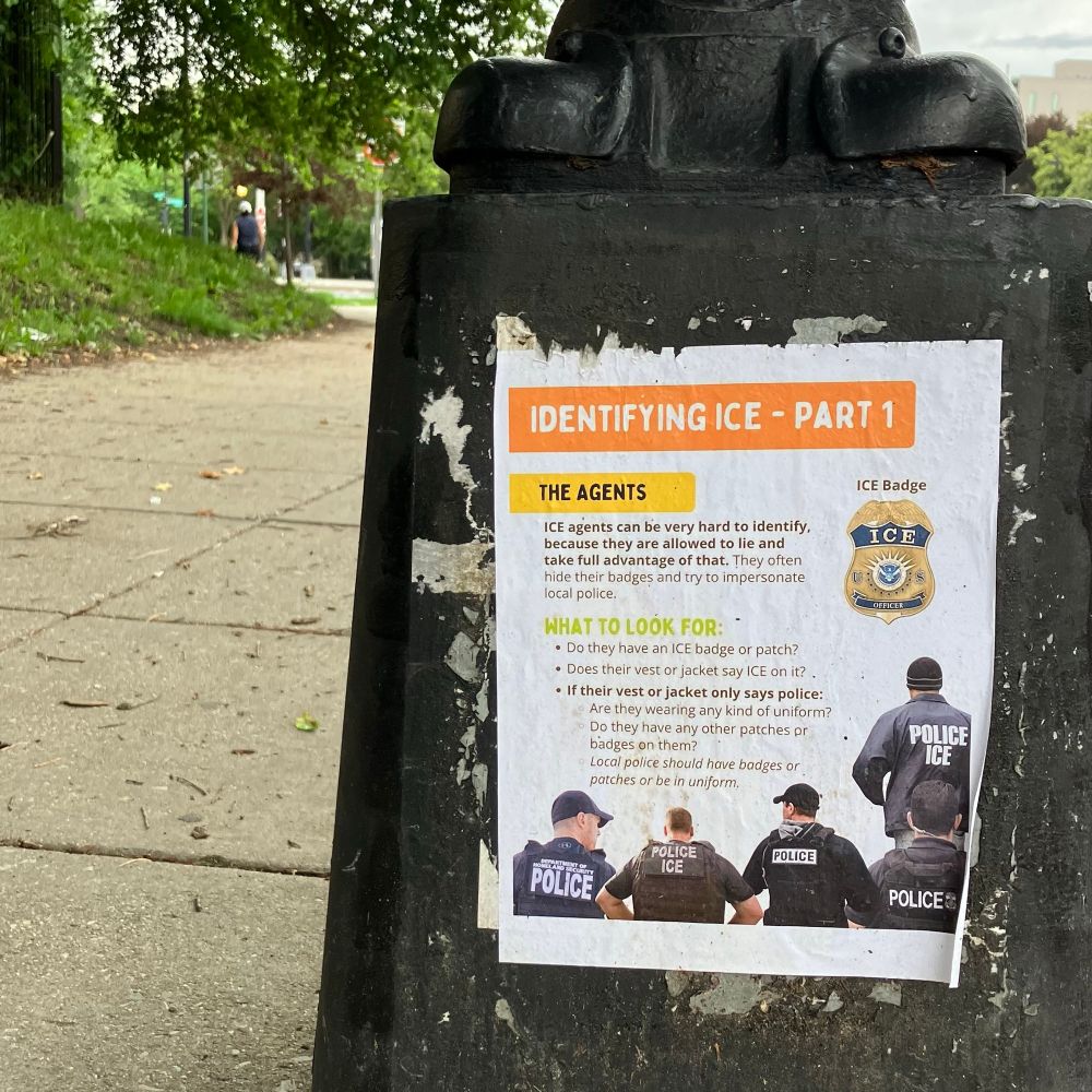 A flyer taped to a lamppost titled “Identifying ICE – Part 1.” It describes how to distinguish ICE agents from local police, noting that agents may hide their badges or wear jackets labeled only “POLICE.” Includes photos of people wearing ICE or police vests, and an image of an ICE badge.