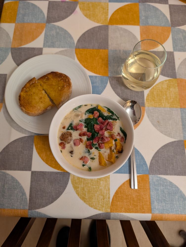 A bowl of Million Dollar Soup and a plate with toasted buttered sourdough on a colourful tablecloth.