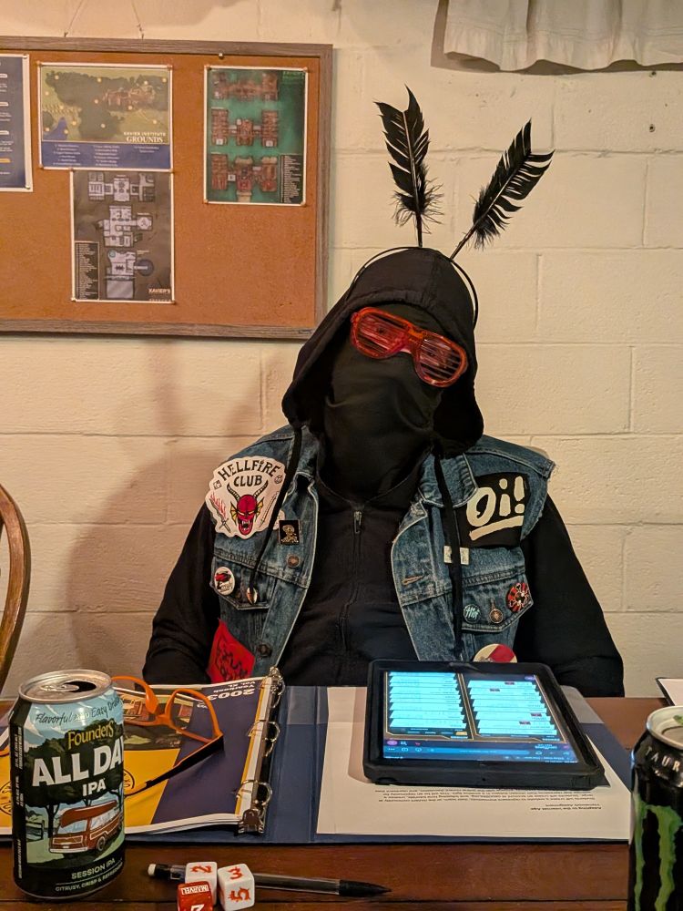 A guy in a battle vest and hoodie with a balaclava and glowing red sunglasses and antennas 