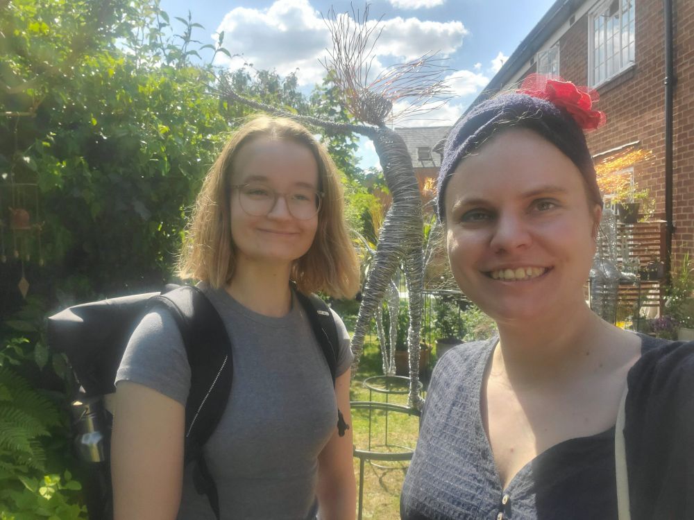 Selfie of Emma and me in a sunny garden of a local artist with one of her wire sculptures of a person in the background