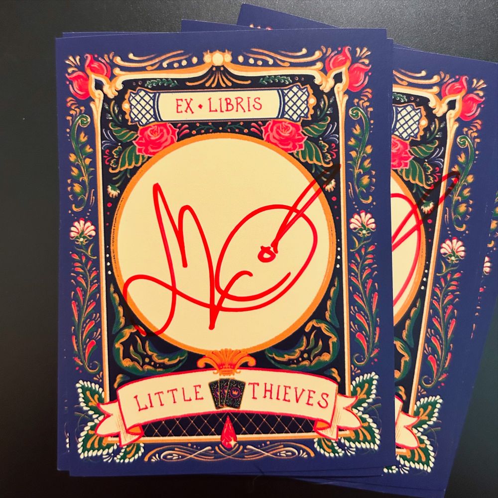 Picture of the very fancy bookplates I drew myself for little thieves! Blue border, black background, cream circle for my signature, all embellished in folk art decorative florals.