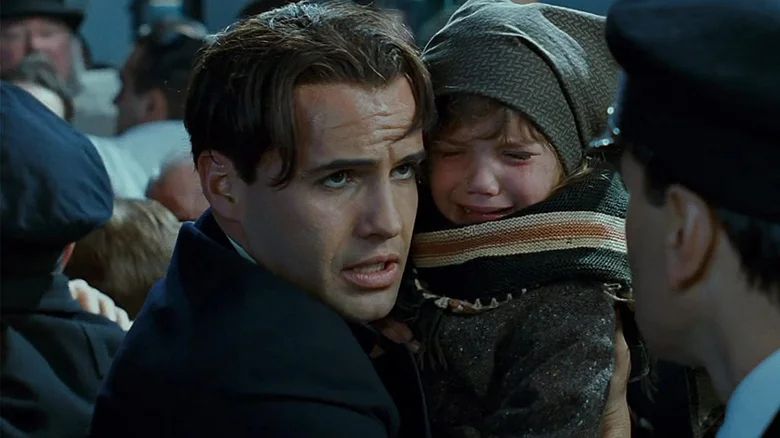 still from the classic film Titanic, depicting Billy Zane as Cal Hockley, a wealthy businessman who has stolen someone's young child and is pretending to be her father to get onto a lifeboat, much like Andrew Cuomo pretended he needed the gynecological records of his sexual harassment victims in an attempt to bully them into silence
